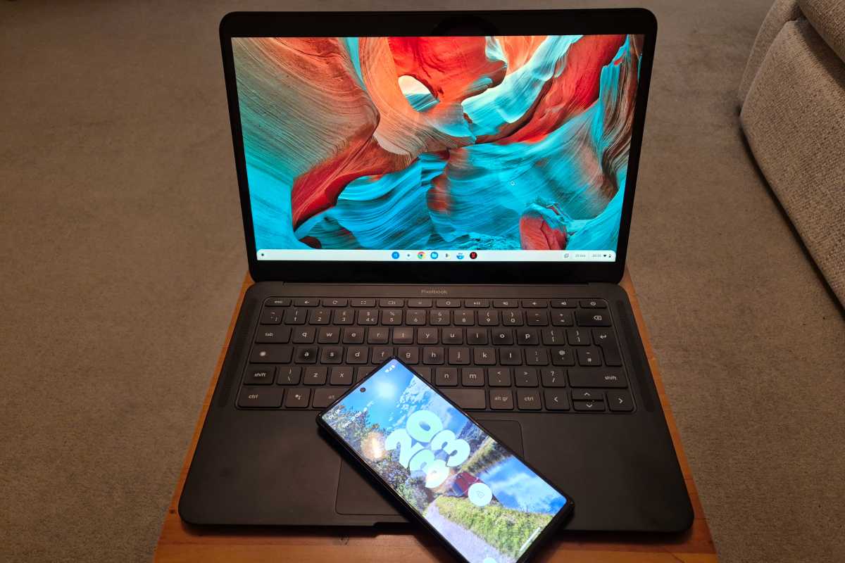 Chromebook laptop on a wooden tray desk with Android phone on keyboard